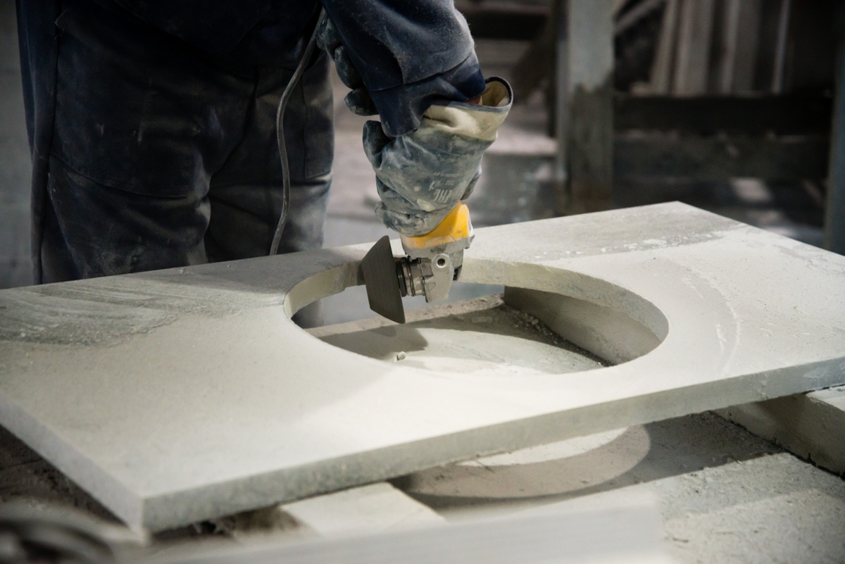 Man polishing marble stone table by small angle grinder. Stone cutter